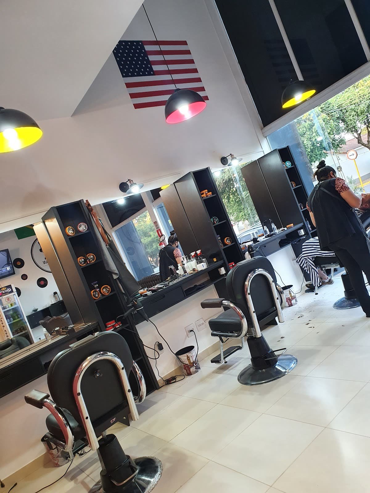 Sala de espera da Barbearia VERSANT, com clientes sentados e neon na parede