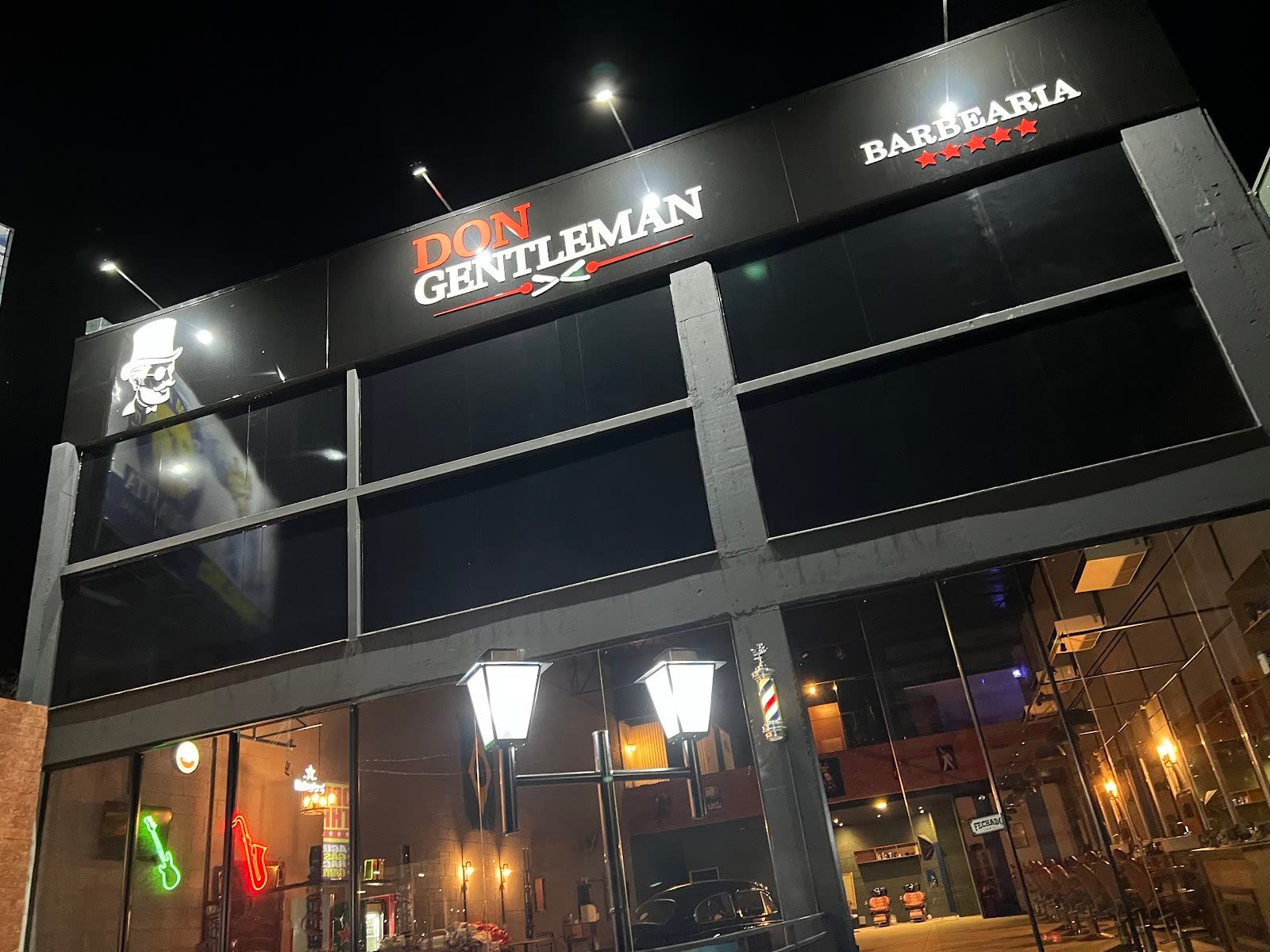 Fachada noturna da Barbearia VERSANT by Don Gentleman, com letreiro de neon e poste de barbeiro, na Av. José Teles de Menezes, 152